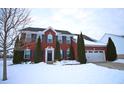 Red brick two-story home with shutters, evergreen trees, and a snowy front yard on a winter day at 1169 Richmond Ln, Greenwood, IN 46143