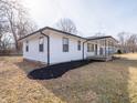 Corner view of the property displaying manicured landscaping, white siding, black trim, and mature trees at 2219 W 59Th St, Indianapolis, IN 46228