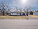 Well-kept single-story home featuring a bright exterior, a paved driveway, and mature trees at 2219 W 59Th St, Indianapolis, IN 46228