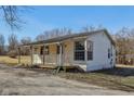 Charming home with a covered porch, large window, and mature trees in the yard at 27 State Road 42 W, Mooresville, IN 46158