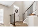 Inviting foyer with wood-look flooring, open stairway, and a wreath adorning the front door at 307 Wakefield Way, Zionsville, IN 46077