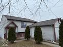 Home featuring a well-maintained lawn, mature landscaping, and side entry garage at 4050 Harmony Dr, Indianapolis, IN 46221