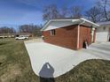 A brick home's side view showcases a concrete driveway, grassy area, and mature trees in the background at 4601 W Bradford Dr, Muncie, IN 47304