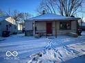 Cozy single-story home with a red door, stone accents, and a snow-covered front yard at 603 W 33Rd St, Anderson, IN 46013