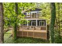 View of a charming home exterior with a multi-level wooden deck and a screen porch surrounded by lush trees at 7082 Muskrat Dr, Nineveh, IN 46164
