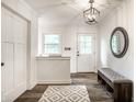 Bright foyer features a stylish light fixture, a round mirror, and a cozy bench with storage at 7082 Muskrat Dr, Nineveh, IN 46164