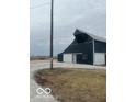 A large, dark metal barn boasts ample storage space and is situated near a gravel driveway at 756 S State Road 13, Lapel, IN 46051