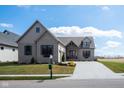 Charming home with gray brick, a manicured lawn, and a paved driveway leading to an attached garage at 16392 Grand Cypress Dr, Noblesville, IN 46060