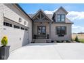 Exterior view of the home, featuring a gray brick facade, a two-car garage, and a welcoming front entrance at 16392 Grand Cypress Dr, Noblesville, IN 46060