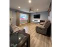 Bright living room with laminate flooring, a ceiling fan, and a wall-mounted entertainment center at 304 Griffin Rd, Indianapolis, IN 46227