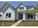 Charming two-story home features a well-manicured lawn, black trim windows, light blue siding, and a welcoming front porch at 4722 Wellswood, Carmel, IN 46033