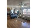 Bright and airy living room with hardwood floors, a ceiling fan, large windows, and an open layout to the kitchen at 6817 Everbloom Ln, Indianapolis, IN 46217