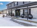 Inviting covered front porch with seating, black railings, and a snow-covered ground at 7089 W 150 N, Greenfield, IN 46140