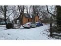 Exterior view of a house with orange siding and bare trees, with a blue and a silver car at 1621 Indiana Ave, Anderson, IN 46012