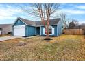 Charming blue home featuring a garage, well-manicured lawn and bright natural light shining through the front window at 169 Meadow Glen Dr, Avon, IN 46123
