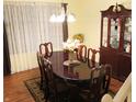 Elegant dining room featuring a wood table set for six, a china cabinet, hardwood floors, and sheer curtains at 5021 Greenside Dr, Indianapolis, IN 46235