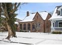 Charming brick home featuring arched windows and snow covered roof, offering classic architectural details at 5444 Carrollton Ave, Indianapolis, IN 46220