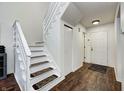 Hallway with a white staircase, wood floors, and a coat closet near the front door at 7459 Quincy Ct, Indianapolis, IN 46254