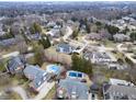 Bird's-eye view of a residential area showcases lush tree coverage, swimming pools, and distinctive home architecture at 12878 Mayfair Ln, Carmel, IN 46032