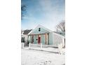 Charming home featuring a covered porch, pink front door, and white picket fence, all surrounded by a blanket of fresh snow at 205 S Market St, Thorntown, IN 46071