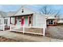 Home exterior featuring a pink door, covered porch with wood beams, and a classic white picket fence at 205 S Market St, Thorntown, IN 46071