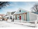 Exterior of a home with a pink door, cozy porch, and a white picket fence surrounded by a snowy landscape at 205 S Market St, Thorntown, IN 46071