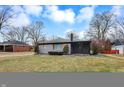 Angle view of a quaint single-story home with grey brick, shutters, and green grass yard at 6144 N Dearborn St, Indianapolis, IN 46220