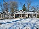 Inviting gray home featuring a front porch decorated with a festive wreath and red planters at 717 Washington Ct, Anderson, IN 46011