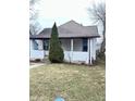 Home exterior featuring neutral siding, complementing a mature evergreen tree in the front yard at 834 N Temple Ave, Indianapolis, IN 46201