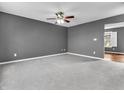 Spacious carpeted living room showcasing a ceiling fan, fresh paint, and a view to the next room at 878 Hollowood Ln, Avon, IN 46123