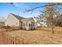 Expansive backyard featuring a well-maintained lawn, a fenced perimeter, and a sunroom attached to the house at 11168 Autumn Harvest Dr, Fishers, IN 46038