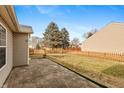 Wide shot of the backyard showing a paver patio, grassy area, privacy fence, and mature trees at 11168 Autumn Harvest Dr, Fishers, IN 46038