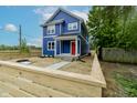 New blue construction with white trim and a red front door protected by a wooden fence at 1305 W 23Rd St, Indianapolis, IN 46208