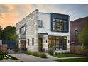 Contemporary home boasts unique stone and siding, accented by black trim, and lush lawn at 2719 Carrollton Ave, Indianapolis, IN 46205
