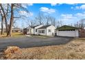 Wide angle view of a house with a detached garage with blacktop driveway under blue skies at 2849 Canterbury Ln, Indianapolis, IN 46220