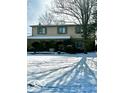 Well-kept two-story residence with a stone base, green shutters and snow-covered front yard on a sunny day at 296 Ironwood Ct, Carmel, IN 46033