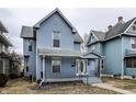 Charming two-story home with blue wood siding, a covered front porch, and updated windows at 323 N Layman Ave, Indianapolis, IN 46219