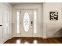 Bright foyer showcasing beautiful hardwood floors, decorative door, and classic wall paneling at 323 N Layman Ave, Indianapolis, IN 46219