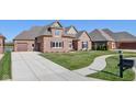 A stylish brick home showcasing a long drive and two-car garage, plus a well-manicured lawn at 4248 Stone Lake Dr, Zionsville, IN 46077