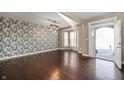 Open-concept living room featuring hardwood floors, large bay window, and decorative wallpaper at 4431 Hickory Stick Row, Greenwood, IN 46143