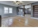 Open-concept living room featuring wood floors, neutral paint, ceiling fan, and a large window for natural light at 515 S East St, Plainfield, IN 46168