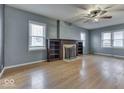 Light-filled living room with wood floors, large windows, fireplace with built-in shelving, and ceiling fan at 515 S East St, Plainfield, IN 46168