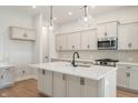 Spacious kitchen boasts white cabinets, stainless steel appliances, pendant lights, and a center island at 555 Gilder Dr, Carmel, IN 46032
