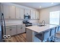 Bright kitchen with stainless steel appliances, gray cabinets, a kitchen island with a sink, and seating at 8623 Lester Pl, Pendleton, IN 46064