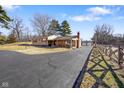 View of home's front exterior and long driveway, featuring stacked firewood on the porch at 1001 N 750 W, Bargersville, IN 46106