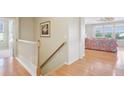 Bright hallway featuring hardwood floors, white railings, and a glimpse of the living room at 12880 Oxbridge Pl, Fishers, IN 46037