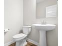 Cozy powder room featuring a pedestal sink, toilet, and a wall-mounted mirror at 15949 Black Willow Ln, Fishers, IN 46040