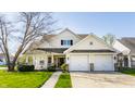 Inviting home featuring a two-car garage, front porch, manicured lawn, and charming architectural details at 3841 Constitution Dr, Carmel, IN 46032