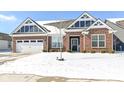 Charming brick home featuring a two-car garage, gabled roof, and inviting front entrance during winter at 9716 Holborn Ave, McCordsville, IN 46055
