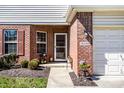 Inviting brick entrance with a storm door, neat landscaping, and an attached garage at 10246 Eller Creek Dr, Fishers, IN 46038